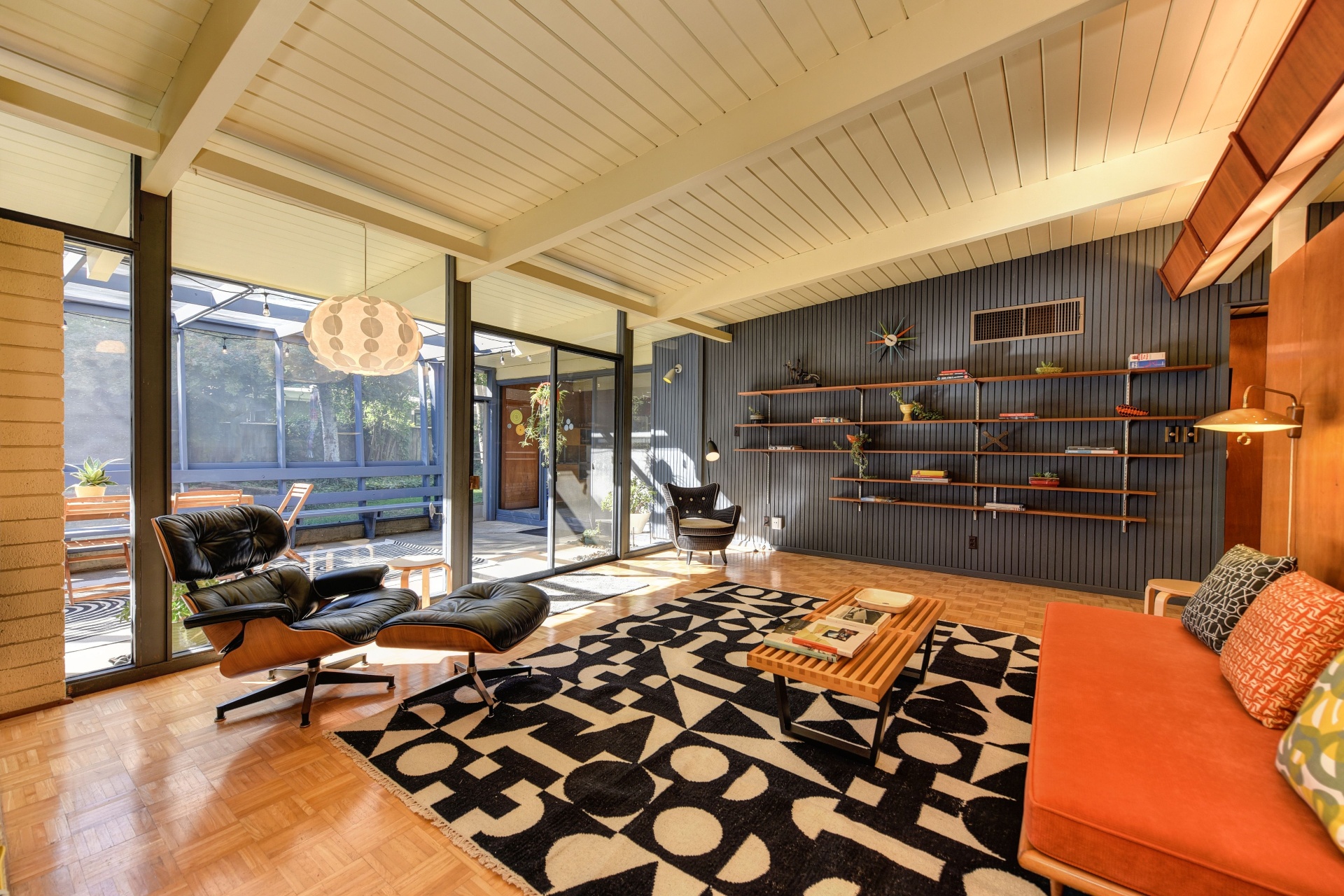 Mid-century modern San Rafael living room with open beam ceiling, Eames lounge chair, and floor-to-ceiling glass